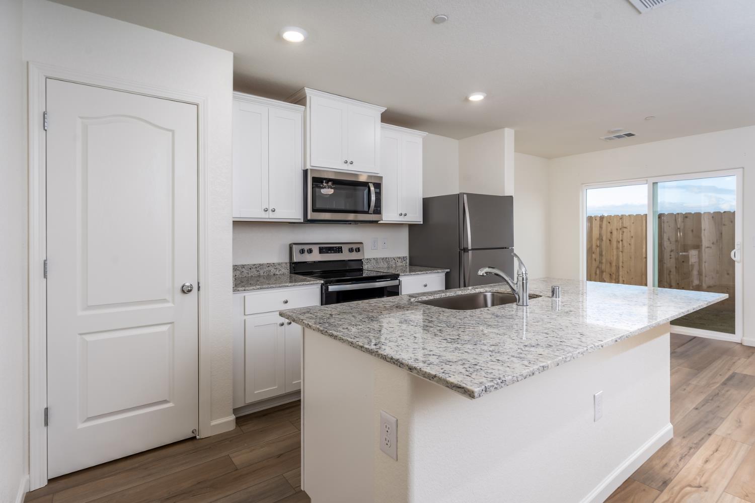 2272 Travis Court Newman, CA 95360 - Photo 3 of 13 a kitchen with kitchen island granite countertop a sink a counter top space appliances and cabinets
