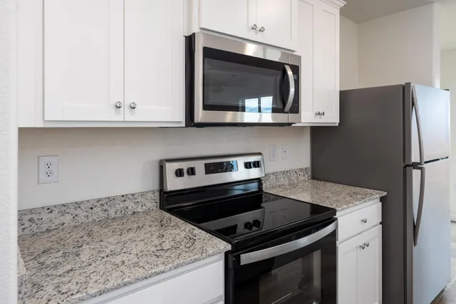 a kitchen with stainless steel appliances granite countertop a stove microwave and refrigerator