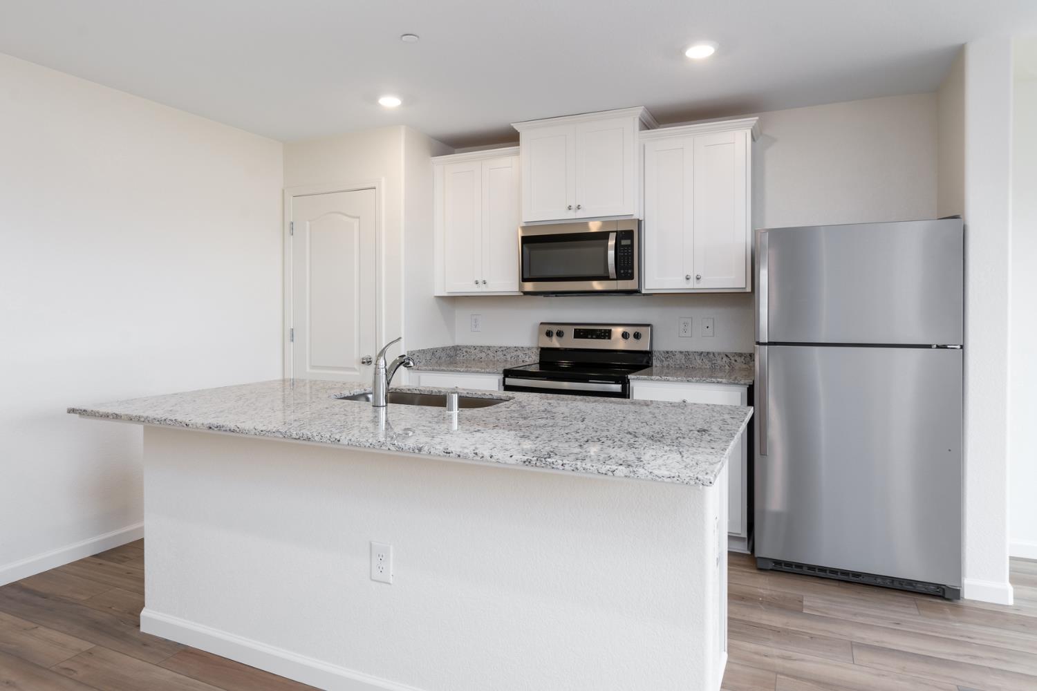 2272 Travis Court Newman, CA 95360 - Photo 5 of 13 a kitchen with stainless steel appliances granite countertop a refrigerator a stove a sink a microwave a refrigerator and white cabinets with wooden floor