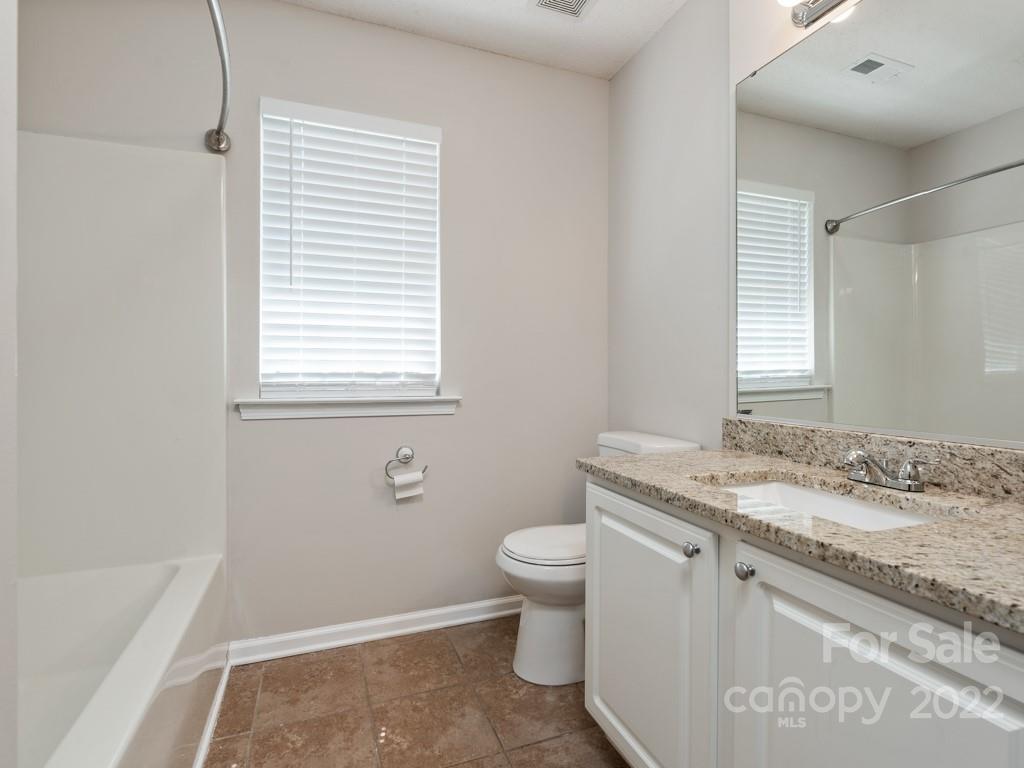 8215 Fox Swamp Road Charlotte, NC 28215 - Photo 19 of 25 a bathroom with a granite countertop sink a toilet and a bathtub