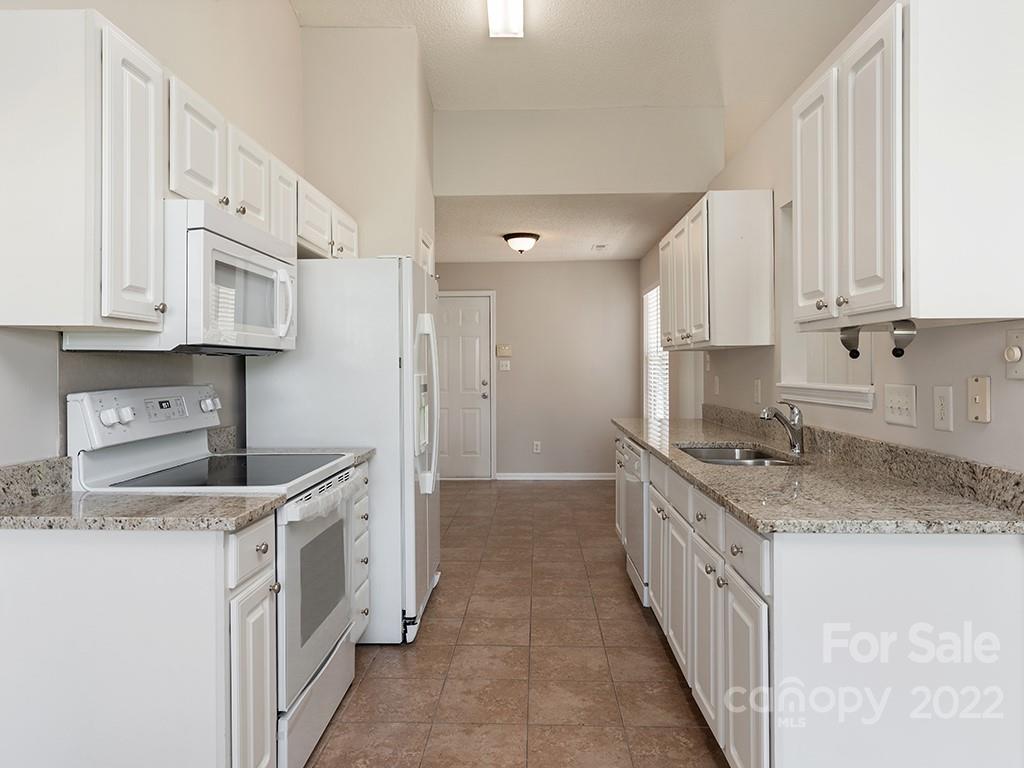 8215 Fox Swamp Road Charlotte, NC 28215 - Photo 7 of 25 a kitchen with stainless steel appliances granite countertop a sink stove and cabinets