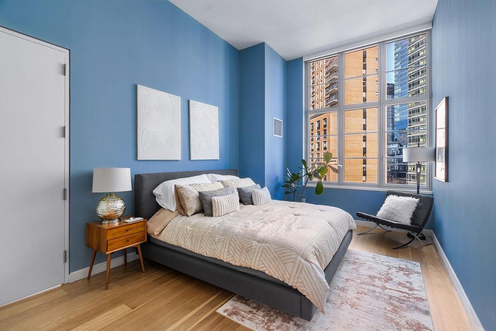 27-28 Thomson Avenue, Unit 804 Queens, NY 11101 - Photo 7 of 17 a bedroom with a bed and wooden floor