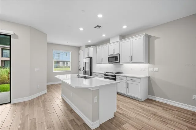 a large kitchen with stainless steel appliances granite countertop a lot of counter space and wooden floor