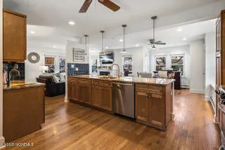 a kitchen with stainless steel appliances kitchen island granite countertop a sink counter space cabinets and a wooden floor