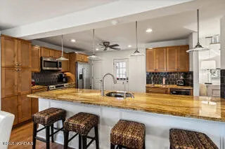 a kitchen with stainless steel appliances granite countertop a stove top oven a sink a dining table and chairs with wooden floor