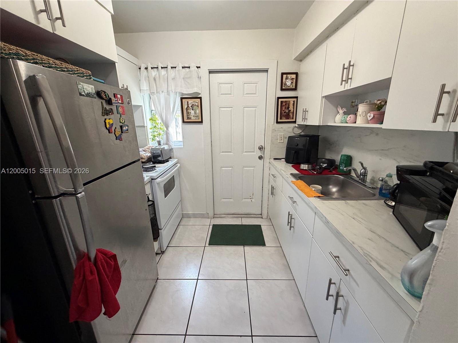 3361 Southwest 28th Street Miami, FL 33133 - Photo 12 of 17 a kitchen with stainless steel appliances a refrigerator sink and cabinets