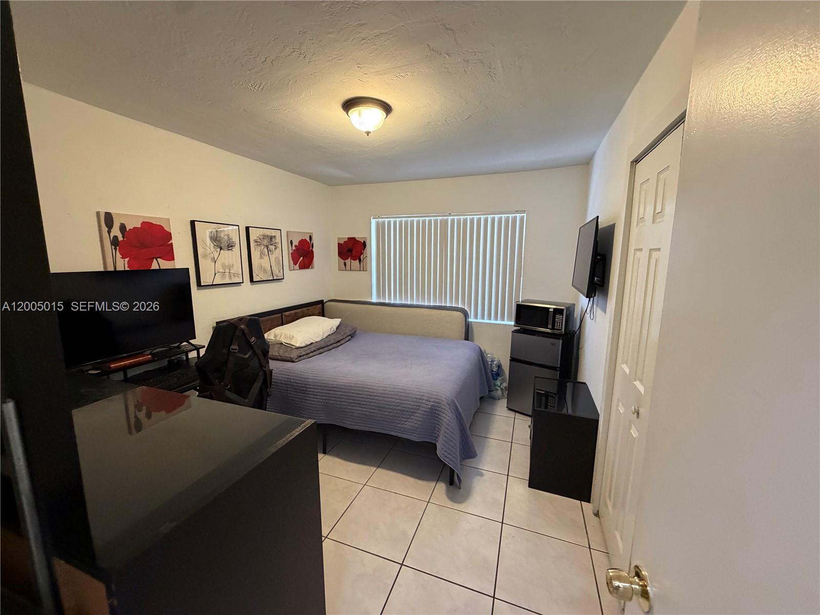 3361 Southwest 28th Street Miami, FL 33133 - Photo 14 of 17 a bedroom with a bed and a refrigerator