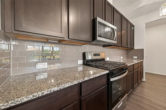 a kitchen with granite countertop wooden cabinets and a stove top oven