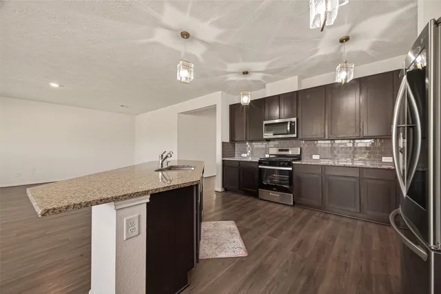 a kitchen with stainless steel appliances granite countertop a sink a stove and refrigerator