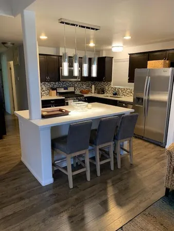 a kitchen with stainless steel appliances a dining table chairs and wooden floor