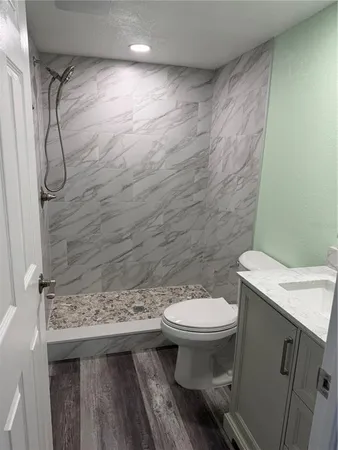 a bathroom with a granite countertop toilet and a sink