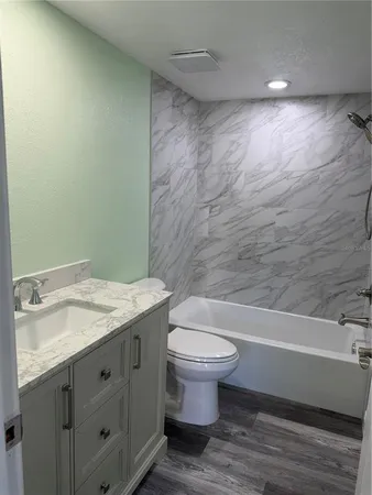 a bathroom with a granite countertop toilet a sink and bathtub