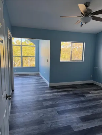 a view of an empty room with a window and wooden floor