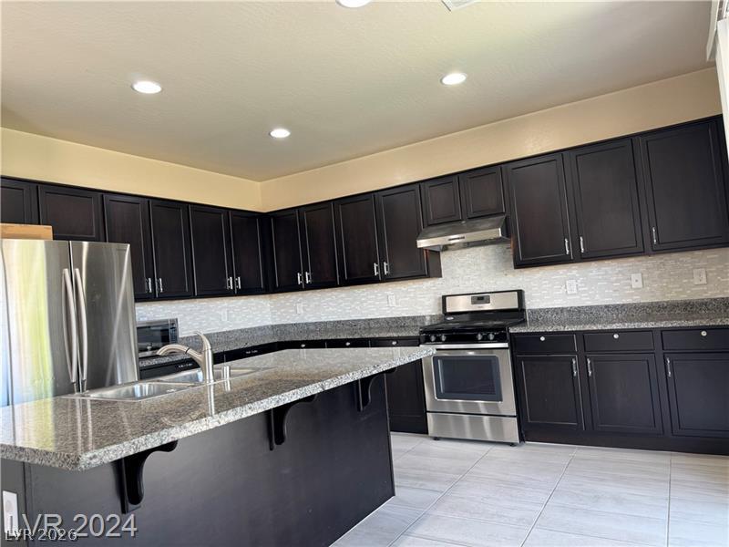 9056 Tony Ridge Avenue Las Vegas, NV 89148 - Photo 6 of 32 Culinary delights await in this modern kitchen with granite countertops and stainless steel appliances.