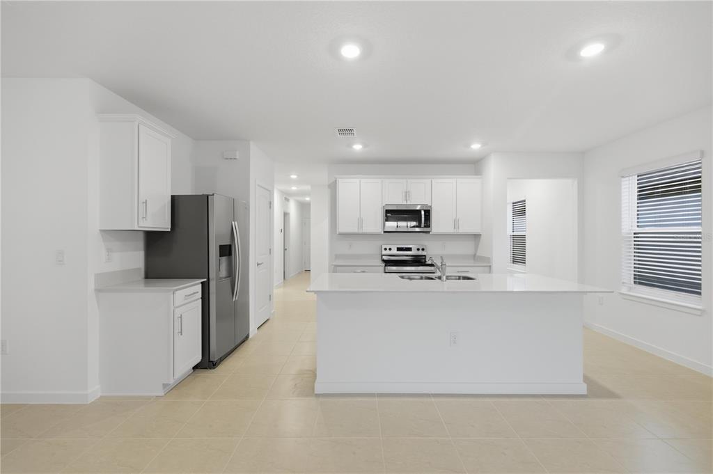 6760 Southwest 90th Loop Ocala, FL 34476 - Photo 11 of 28 a large kitchen with stainless steel appliances a refrigerator a stove top oven a sink and cabinets