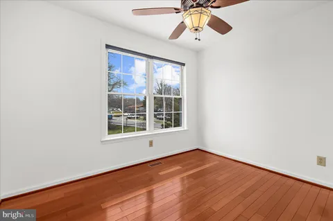 an empty room with a chandelier fan and wooden floor
