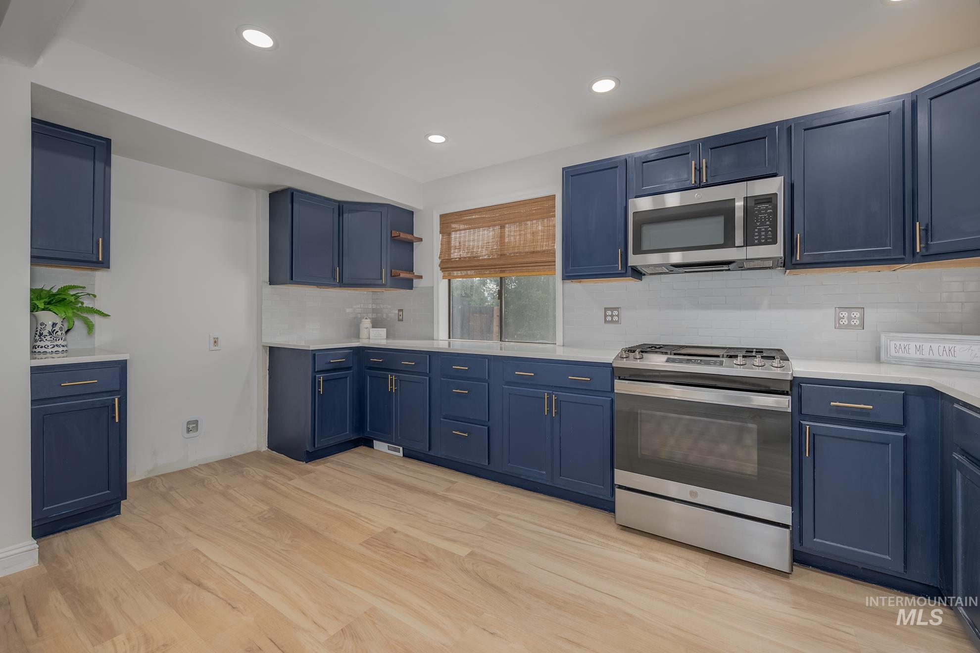 61 Southwest 4th Street Ontario, OR 97914 - Photo 10 of 42 Kitchen featuring blue cabinetry, white countertops, stainless steel appliances, white subway tile backsplash, and wood-finish flooring