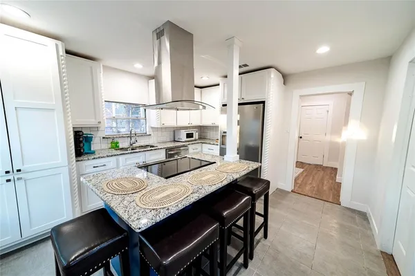 a kitchen with granite countertop a table chairs stainless steel appliances and cabinets