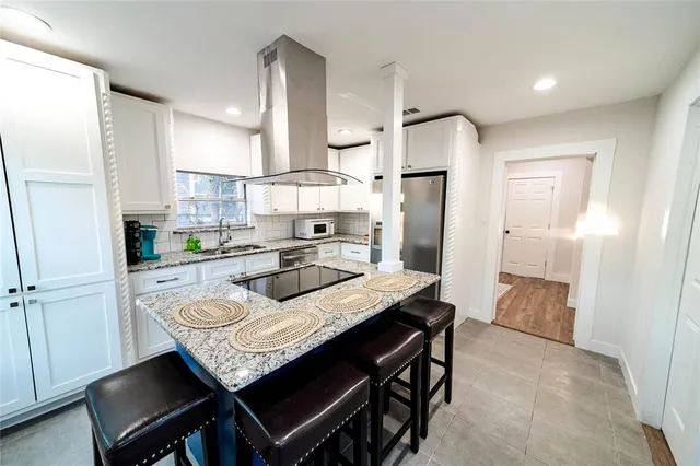 a kitchen with granite countertop a table chairs stainless steel appliances and cabinets