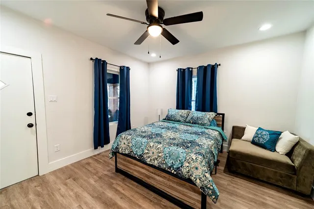 a bedroom with a bed ceiling fan and a wooden floor