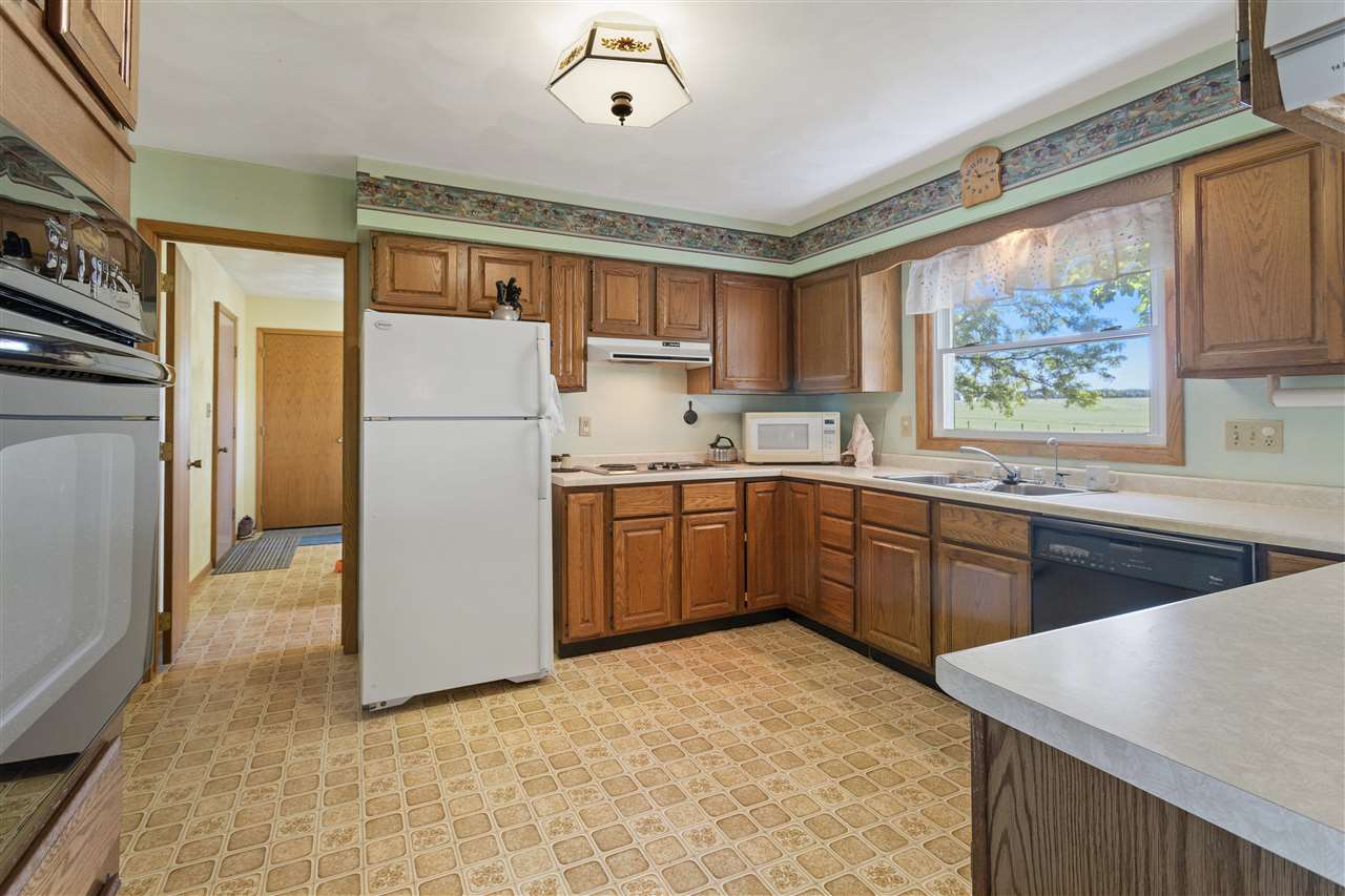 7365 East Ridott Road Ridott, IL 61067 - Photo 10 of 26 a kitchen with a refrigerator a stove a sink dishwasher and wooden cabinets