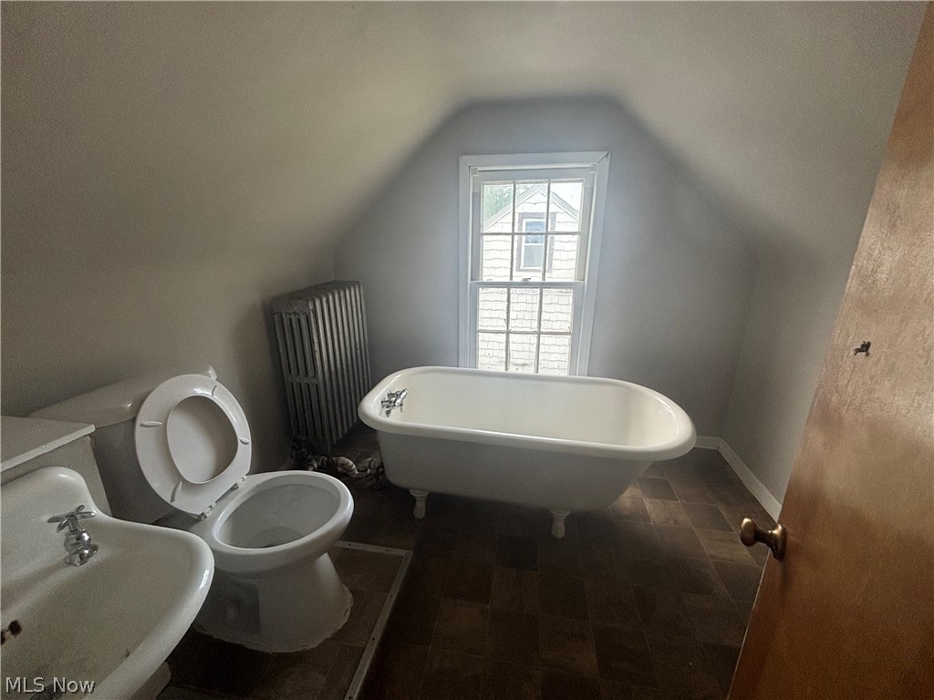 3030 Keswick Road Cleveland, OH 44120 - Photo 12 of 15 Bathroom featuring lofted ceiling, radiator, a bathing tub, sink, and toilet