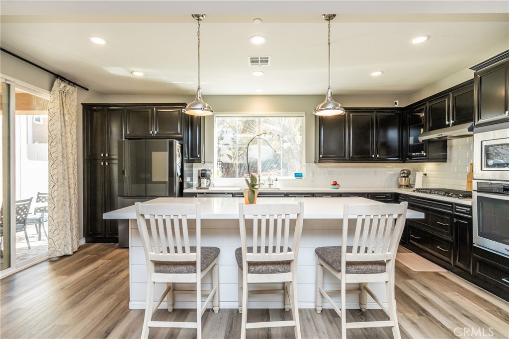 32390 Magee Lane Temecula, CA 92592 - Photo 13 of 75 a kitchen with stainless steel appliances granite countertop a stove a refrigerator a kitchen island a dining table and chairs