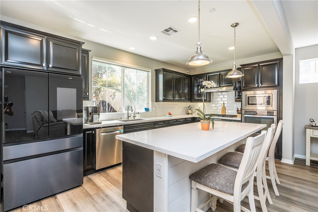 32390 Magee Lane Temecula, CA 92592 - Photo 14 of 75 a open kitchen with stainless steel appliances granite countertop a stove top oven a sink dishwasher a dining table and chairs with wooden floor