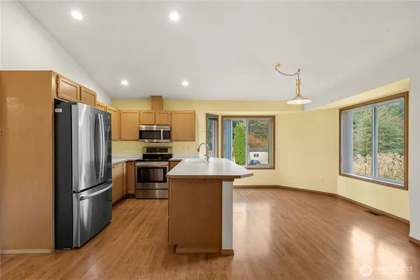 a kitchen with kitchen island wooden floors appliances and window