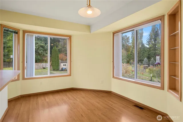 a view of an empty room with a window and wooden floor
