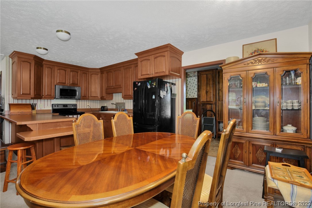 6015 Goldsboro Road Wade, NC 28395 - Photo 20 of 50 a kitchen with stainless steel appliances granite countertop a refrigerator a stove a sink a dining table and chairs with wooden floor