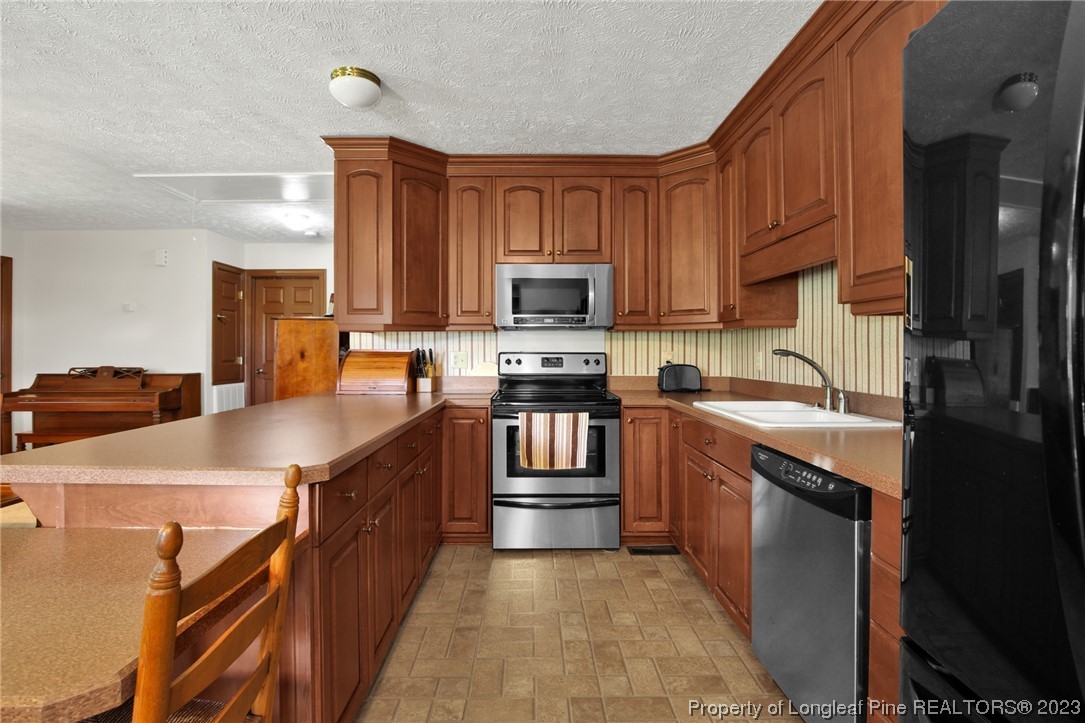 6015 Goldsboro Road Wade, NC 28395 - Photo 21 of 50 a kitchen with stainless steel appliances granite countertop a stove top oven a sink dishwasher and a refrigerator with wooden cabinets