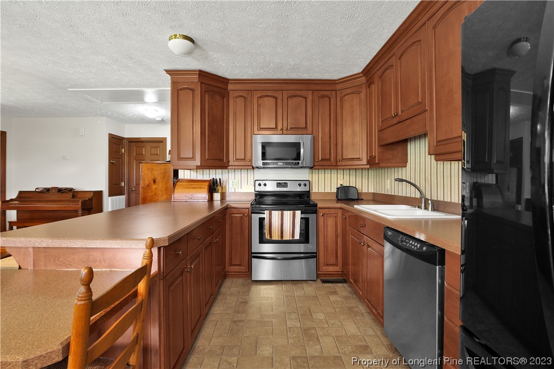 6015 Goldsboro Road Wade, NC 28395 - Photo 22 of 50 a kitchen with stainless steel appliances granite countertop a stove top oven a sink dishwasher and a refrigerator with wooden cabinets