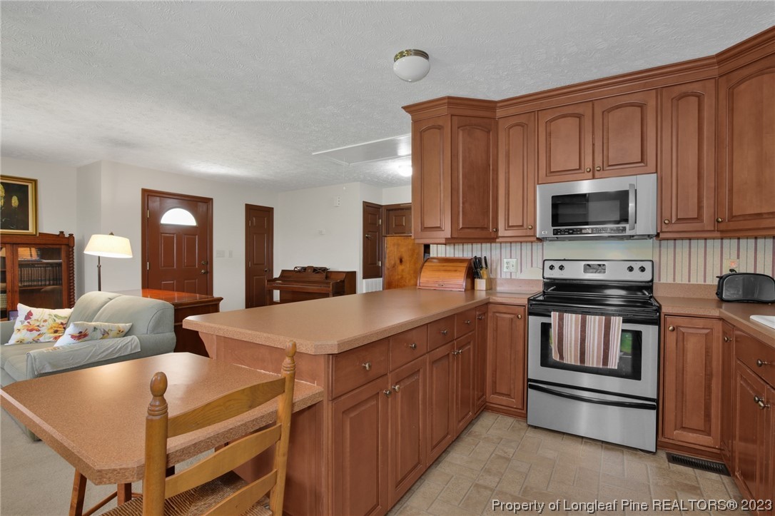 6015 Goldsboro Road Wade, NC 28395 - Photo 26 of 50 a kitchen with stainless steel appliances granite countertop a stove top oven a sink dishwasher and a microwave oven with wooden cabinets