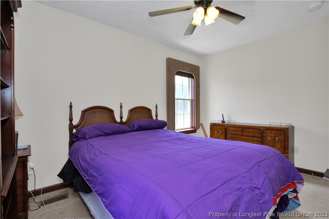 6015 Goldsboro Road Wade, NC 28395 - Photo 31 of 50 a bedroom with a bed and a chandelier