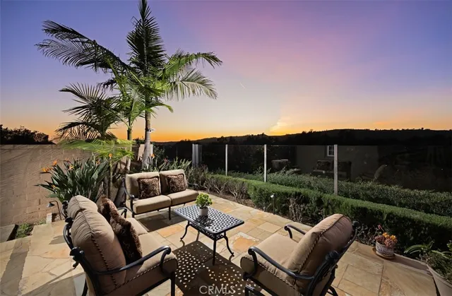 a view of a patio with couches table and chairs under an umbrella with palm trees