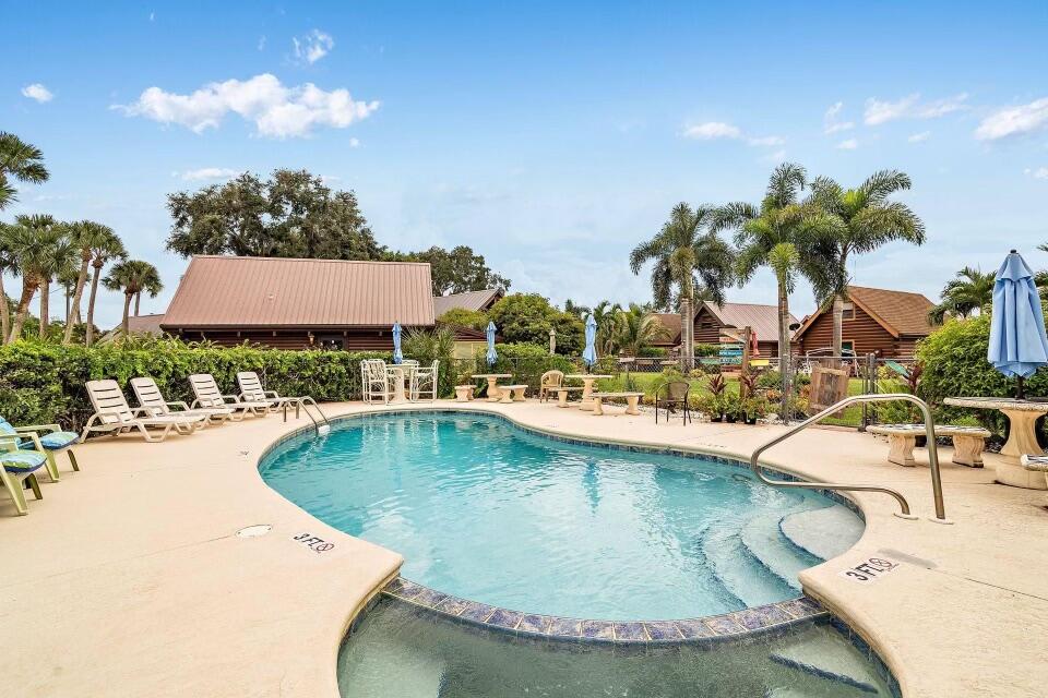 8348 Highway 441 Okeechobee, FL 34974 - Photo 23 of 25 a view of a swimming pool with a table and chairs under an umbrella