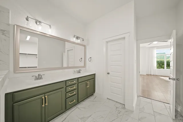 a bathroom with a double vanity sink a large mirror and a bathtub