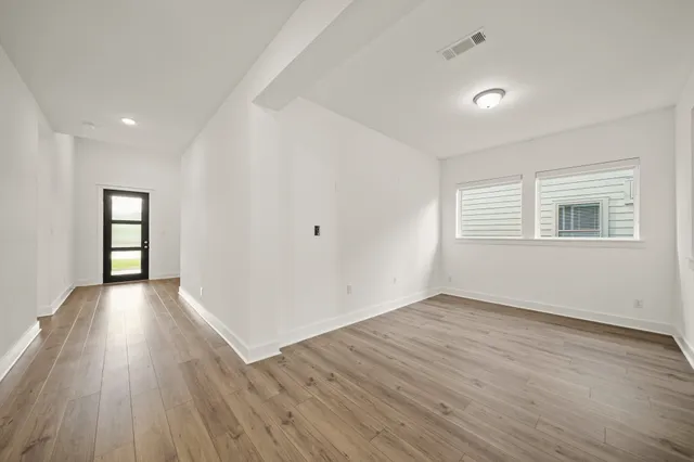 an empty room with wooden floor and windows