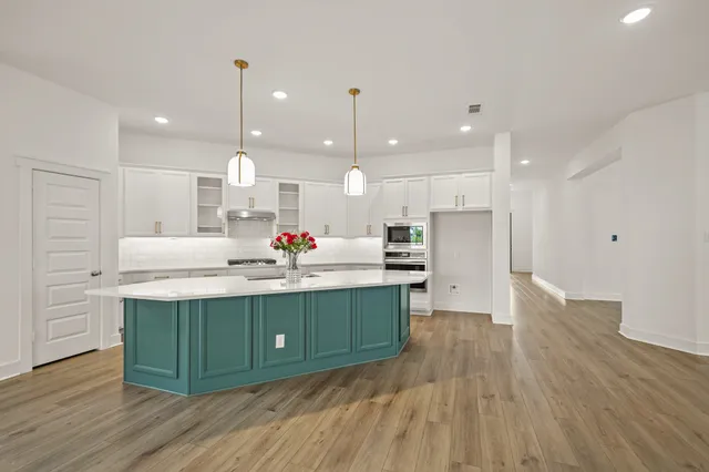 a kitchen with stainless steel appliances granite countertop a sink a stove a refrigerator and a wooden floor