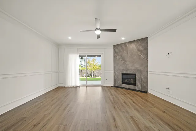 an empty room with wooden floor fireplace and windows