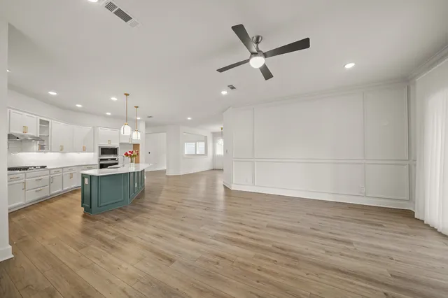 a large kitchen with kitchen island a sink dishwasher stove and white cabinets with wooden floor