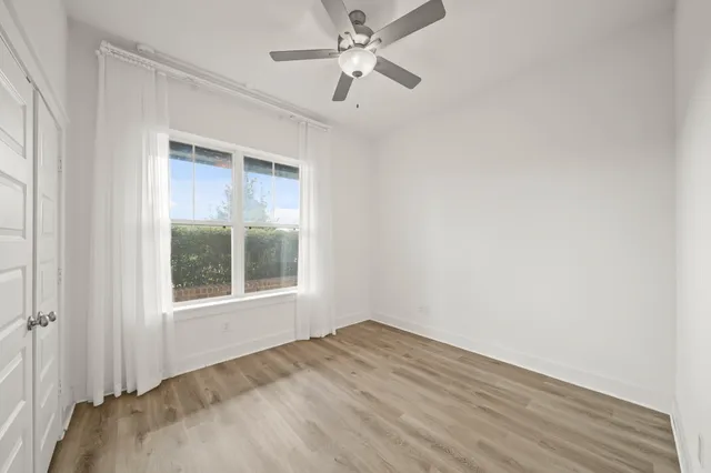an empty room with a window and a ceiling fan