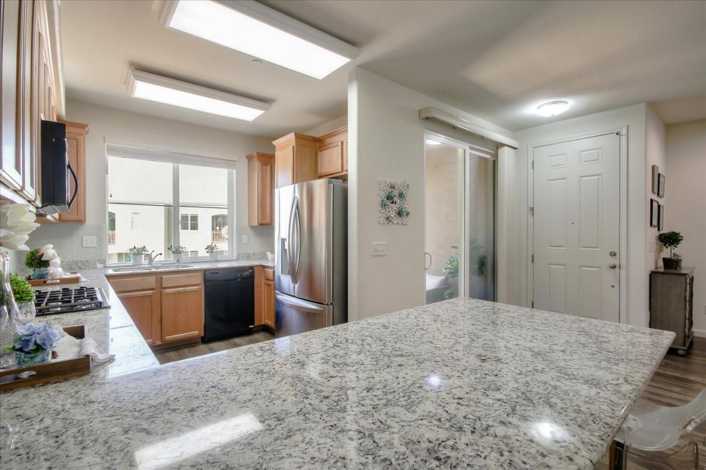 4712 Norris Canyon Road, Unit 202 San Ramon, CA 94583 - Photo 9 of 30 a kitchen with stainless steel appliances kitchen island granite countertop a refrigerator stove top oven and sink