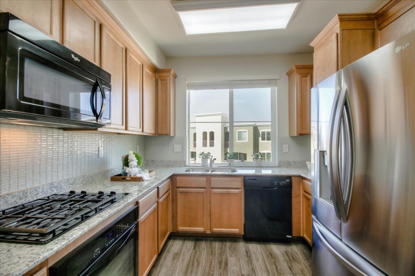 4712 Norris Canyon Road, Unit 202 San Ramon, CA 94583 - Photo 10 of 30 a kitchen with stainless steel appliances granite countertop a stove a sink dishwasher a refrigerator and wooden cabinets