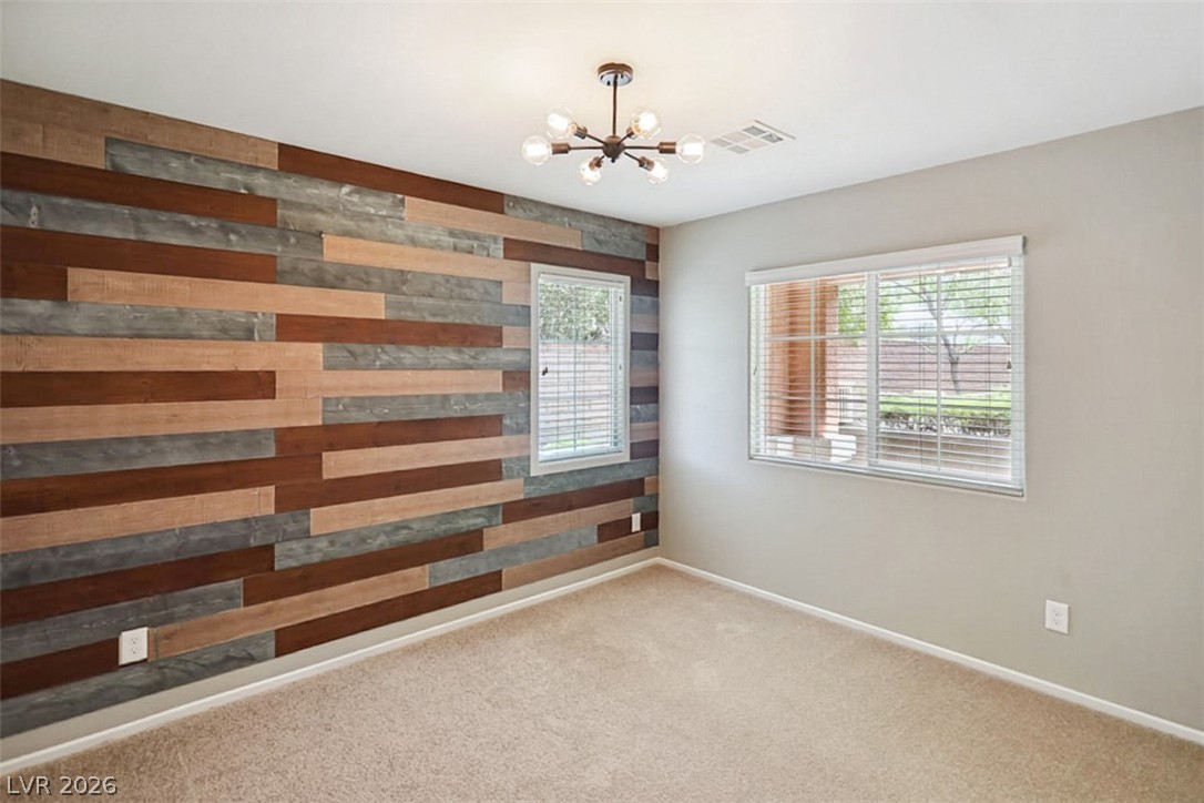 9940 Sable Point Street Las Vegas, NV 89178 - Photo 13 of 40 Carpeted empty room featuring a chandelier, wood walls, and baseboards