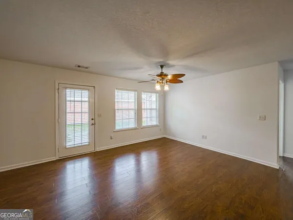 a view of an empty room with a window and wooden floor