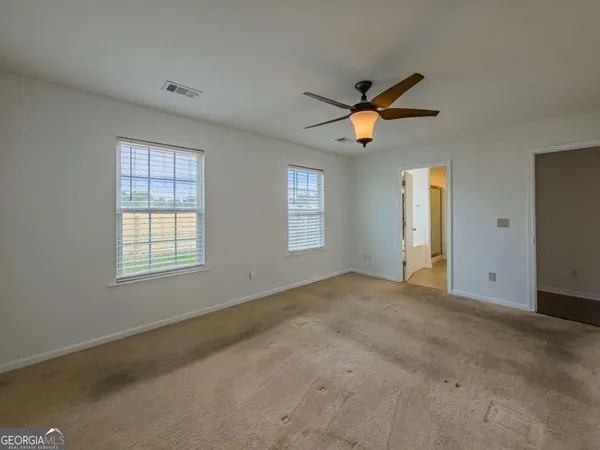 a view of empty room with window and ceiling fan