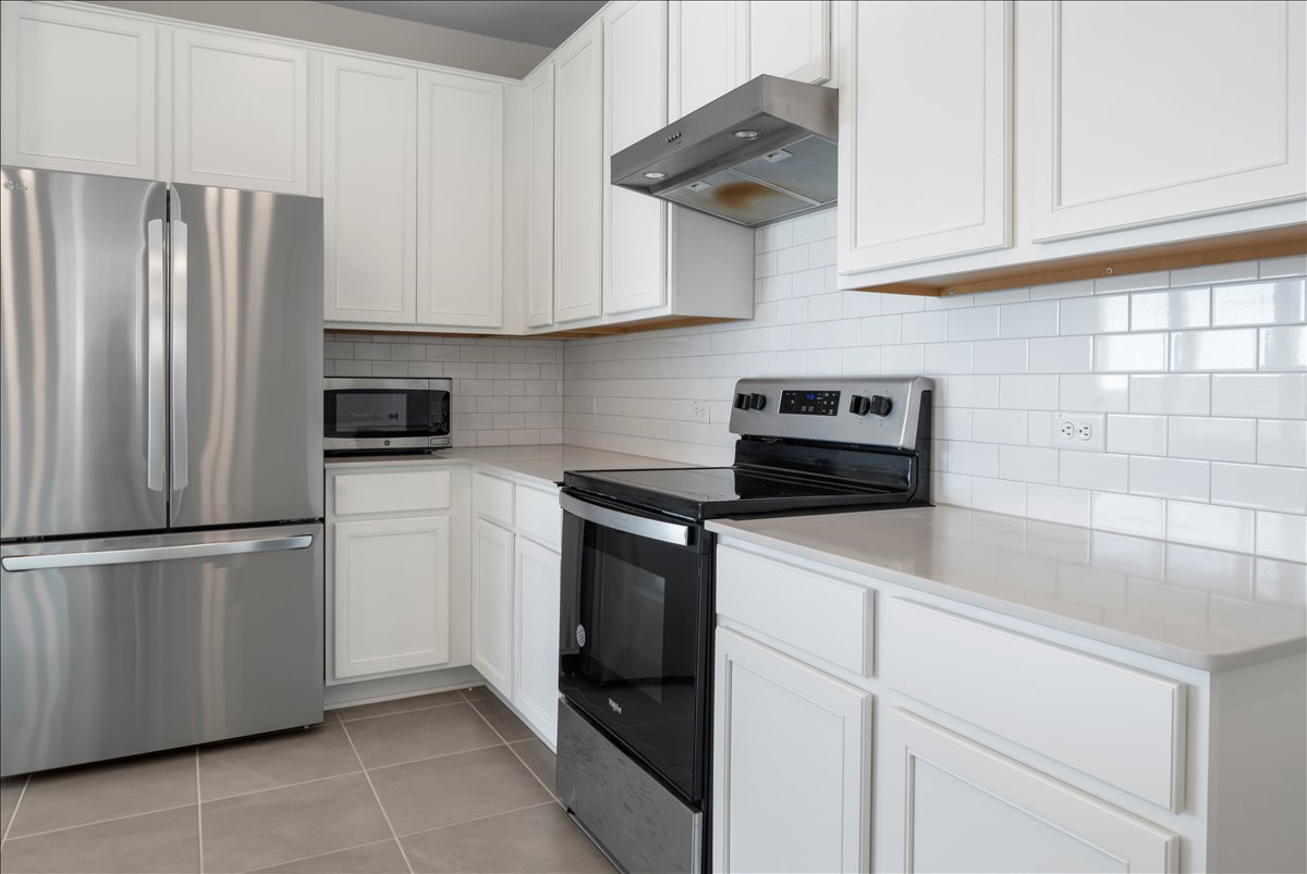 18501 Spotted Eagle Lane Elgin, TX 78621 - Photo 9 of 40 A well-equipped kitchen features bright white cabinetry and gleaming stainless steel appliances.