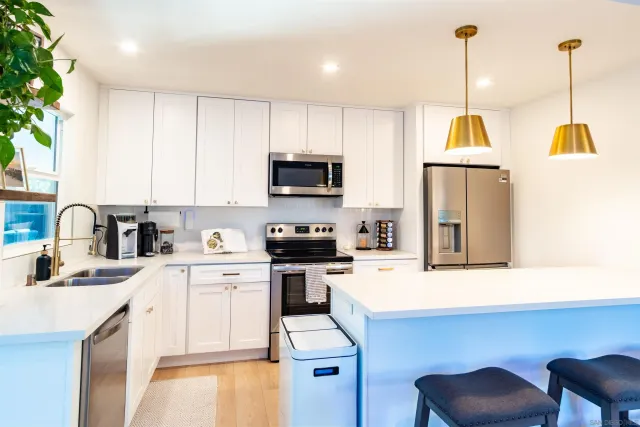 a kitchen with stainless steel appliances kitchen island granite countertop a sink a stove and a wooden floors